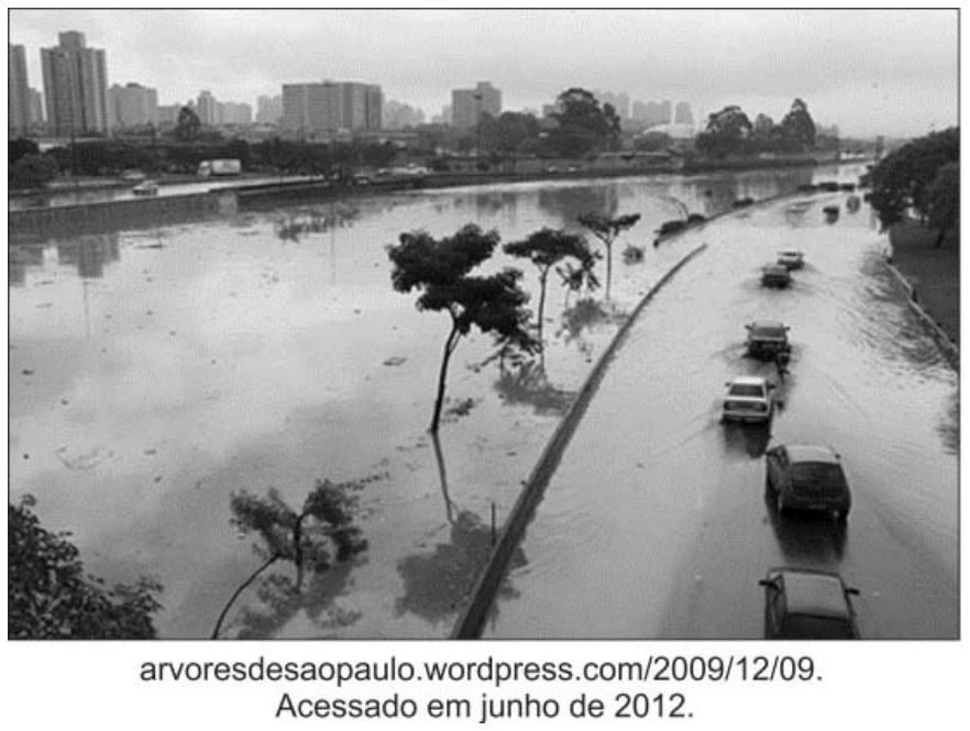 Fotografia da Marginal Tietê em São Paulo alagada por enchente, com pistas cobertas de água e veículos trafegando com dificuldade.