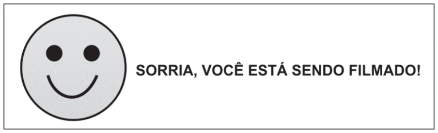 Placa retangular contendo um desenho de rosto sorridente à esquerda e a frase "SORRIA, VOCÊ ESTÁ SENDO FILMADO!" à direita.