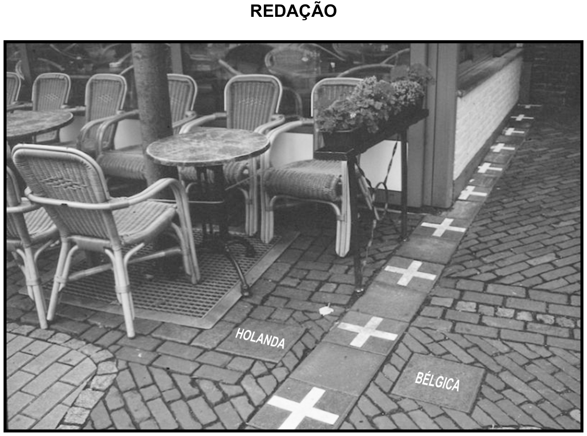 Fotografia em preto e branco de um café ao ar livre no município de Baarle-Nassau/Baarle-Hertog, cortado pela linha de fronteira entre os dois países. Uma faixa no calçamento com cruzes brancas divide o espaço, com as inscrições "HOLANDA" no chão de um lado e "BÉLGICA" do outro.