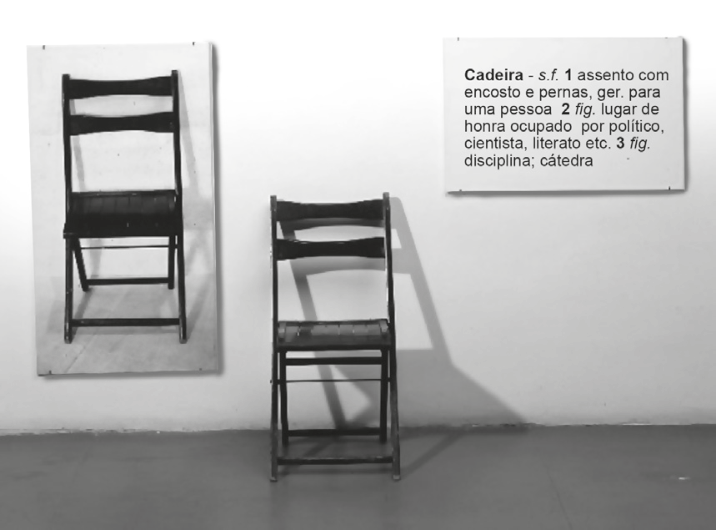 Obra de arte conceitual "One and Three Chairs" (1965), de Joseph Kosuth, composta por uma fotografia de cadeira pendurada à esquerda, a cadeira real de madeira apoiada no chão ao centro e um painel com a definição de dicionário da palavra "Cadeira" à direita.