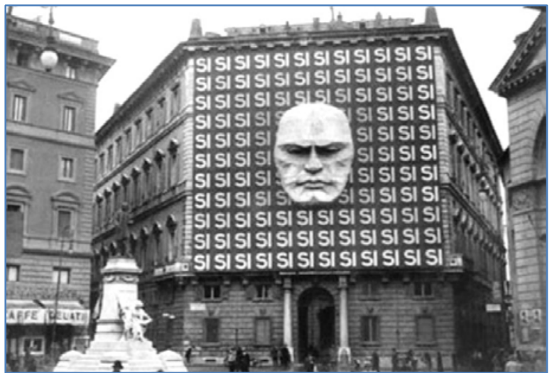 F1 Fachada do edifício do Partido Nacional Fascista com a escultura do rosto de Benito Mussolini ao centro de um gigantesco painel com a palavra "SI" repetida dezenas de vezes.