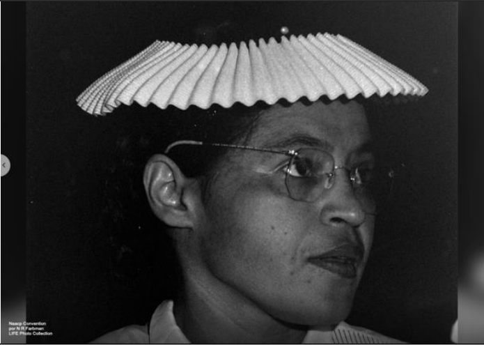 Fotografia em preto e branco de uma mulher negra usando óculos e um chapéu claro com pregas, olhando para a direita. Há um pequeno crédito à LIFE Photo Collection no canto inferior esquerdo.