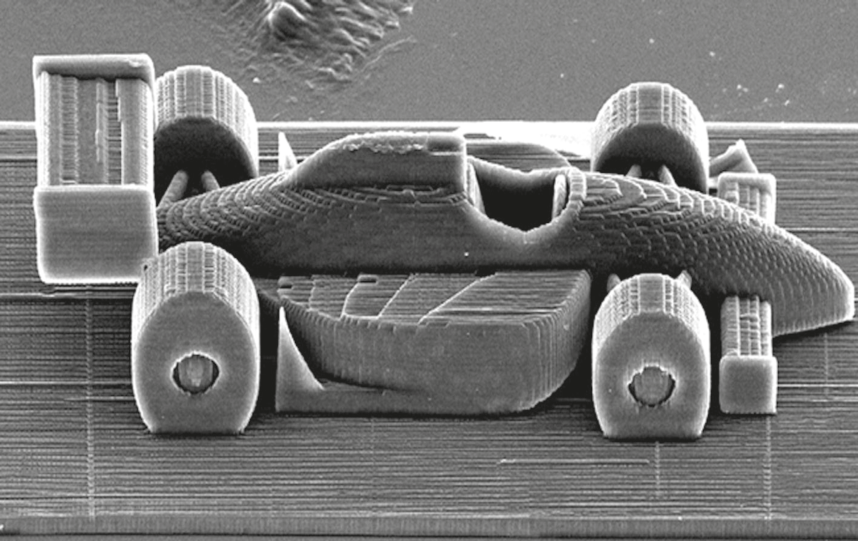 Imagem ampliada de uma microescultura tridimensional de um carro de Fórmula 1 impressa em resina por laser