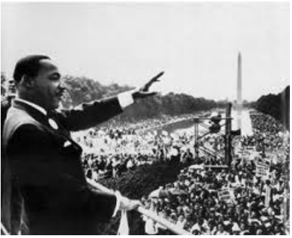 Fotografia em preto e branco de Martin Luther King discursando para uma grande multidão com o obelisco do Monumento a Washington ao fundo.