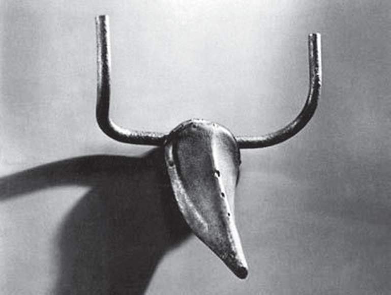 Escultura Cabeça de touro, composta por um selim de bicicleta apontado para baixo e um guidão curvado para cima fixado na sua extremidade superior, assemelhando-se aos chifres e ao focinho de um touro.