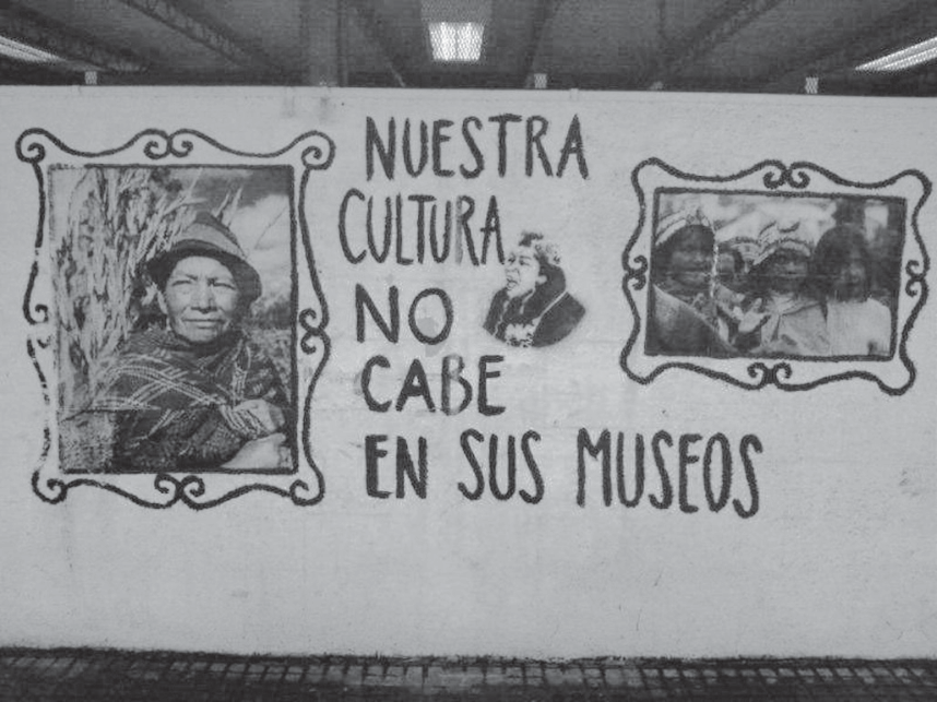 F1 Mural pintado em um muro com duas ilustrações de pessoas indígenas inseridas em molduras decorativas desenhadas e, entre elas, a frase em espanhol: "NUESTRA CULTURA NO CABE EN SUS MUSEOS".