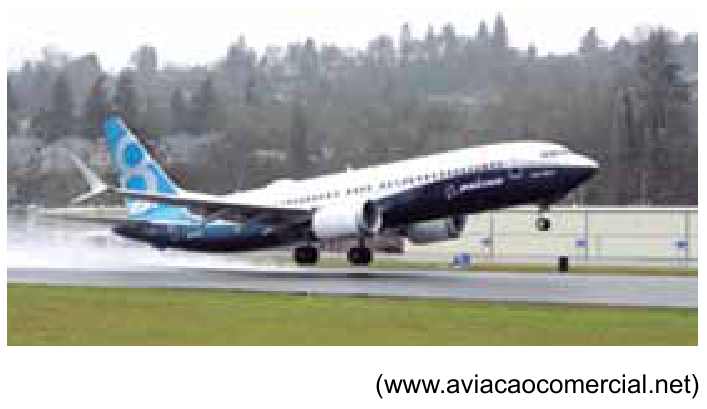 Avião comercial em processo de aterrissagem em pista com água, com crédito ao site aviacaocomercial.net na parte inferior direita