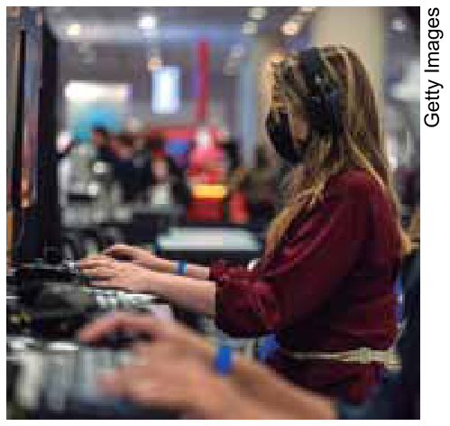 Mulher de perfil usando máscara e fone de ouvido, operando um computador em um evento de jogos