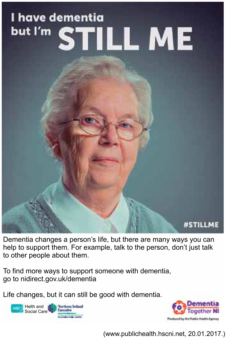 Cartaz de campanha publicitária sobre demência. Na parte superior, sobre a foto de uma mulher idosa de cabelos curtos grisalhos e óculos de grau, lê-se: "I have dementia but I’m STILL ME" e a hashtag "#STILLME" no canto inferior direito da fotografia. Abaixo da foto, constam os seguintes textos: "Dementia changes a person’s life, but there are many ways you can help to support them. For example, talk to the person, don’t just talk to other people about them. / To find more ways to support someone with dementia, go to nidirect.gov.uk/dementia / Life changes, but it can still be good with dementia." No rodapé, constam os logotipos de "Health and Social Care", "Northern Ireland Executive" e "Dementia Together NI", acompanhados do crédito "(www.publichealth.hscni.net, 20.01.2017.)".