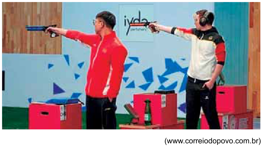 Dois atletas de tiro esportivo perfilados empunhando pistolas de ar comprimido com um braço esticado em direção ao alvo.
