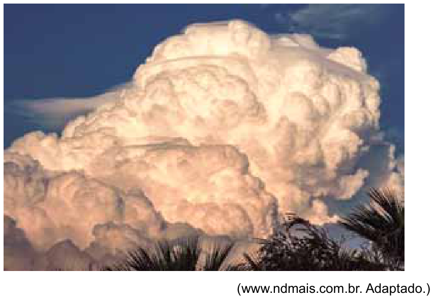 Fotografia de uma grande formação de nuvem de tempestade do tipo cumulonimbus, de grande desenvolvimento vertical, com topo denso e esbranquiçado iluminado pelo sol, contrastando com o céu azul e silhuetas de folhas de palmeira em primeiro plano na base inferior. Abaixo da imagem, lê-se: (www.ndmais.com.br. Adaptado.)