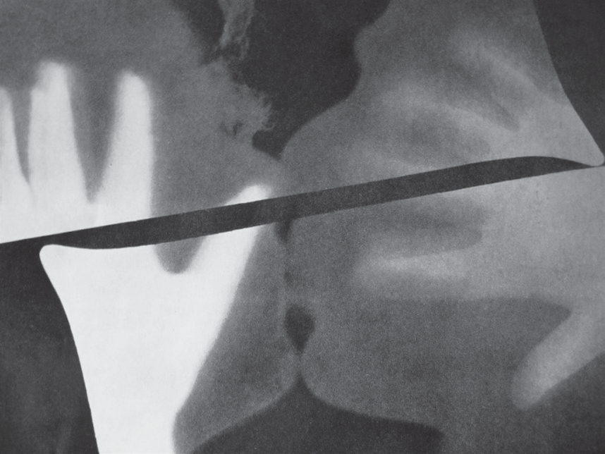 Rayograph (1922), de Man Ray: fotograma em preto e branco que exibe contornos sobrepostos e difusos, lembrando a silhueta de uma mão e perfis faciais, atravessados por uma faixa escura diagonal.