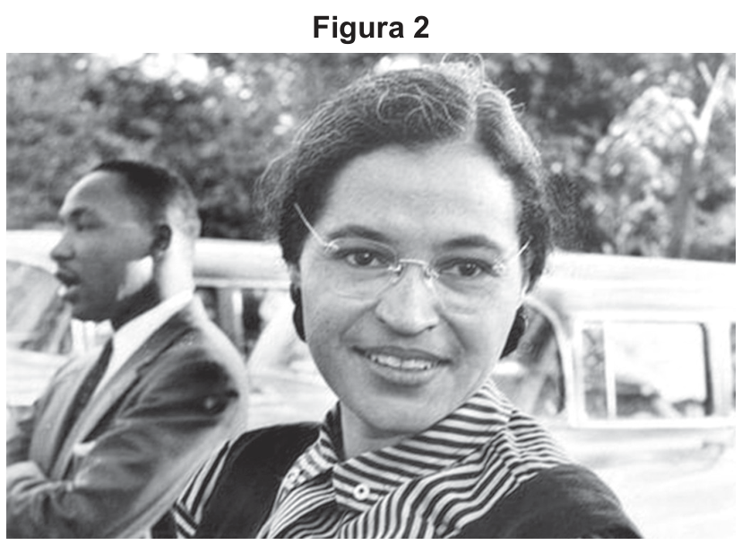 F2 Fotografia em preto e branco de Rosa Parks em primeiro plano, usando óculos e camisa listrada com colete, olhando para a frente com leve sorriso, tendo Martin Luther King Jr. ao fundo à esquerda de perfil.