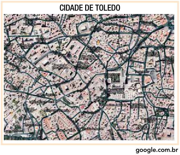 Imagem aérea da malha urbana da cidade de Toledo, com ruas estreitas e traçado sinuoso e irregular de origem medieval, cercadas de construções densas.