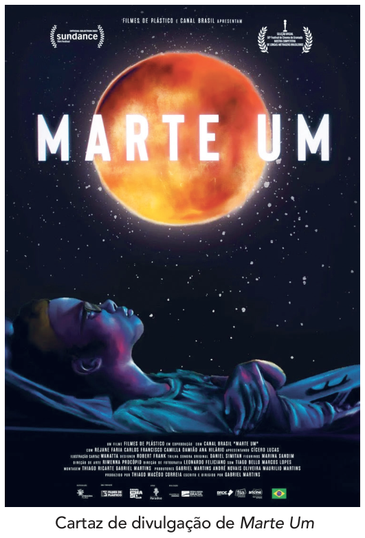 F1 Cartaz de divulgação do filme Marte Um, mostrando um jovem deitado olhando para cima em direção a um grande planeta vermelho e brilhante no céu estrelado, com os dizeres Marte Um.