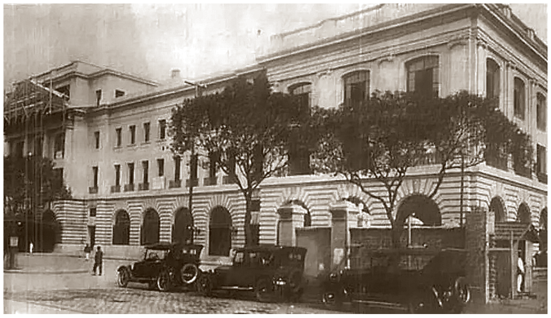 Fotografia antiga em preto e branco da imponente fachada da Estação Ferroviária Leopoldina (Barão de Mauá), com carros de época estacionados em frente.