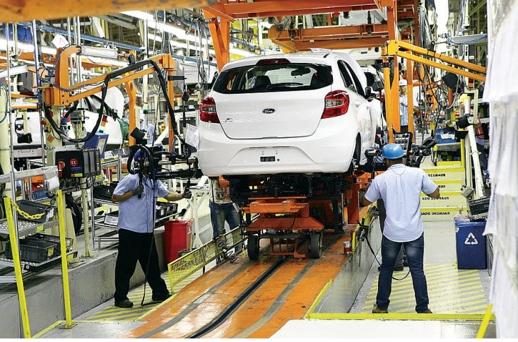 F1 Operários trabalham em linha de montagem industrial de automóveis.