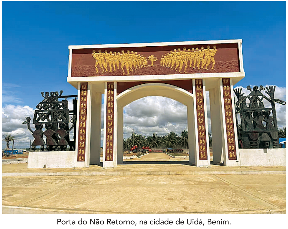 Monumento da Porta do Não Retorno, em Uidá, Benim, composto por um grande arco com baixos-relevos de pessoas escravizadas e esculturas laterais. Abaixo da imagem, a legenda: "Porta do Não Retorno, na cidade de Uidá, Benim."