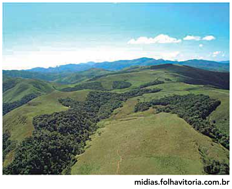F1 Fotografia aérea de uma paisagem montanhosa de pastagem com fragmentos de mata conectados por um corredor florestal.