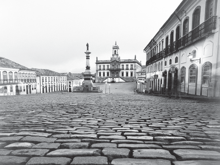 F2 Vista da Praça Tiradentes em Ouro Preto, pavimentada com calçamento de pedras (pé de moleque), cercada por casario colonial e com o Museu da Inconfidência ao fundo.