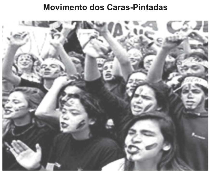 F1 Fotografia em preto e branco de vários jovens reunidos em manifestação com os rostos pintados de preto e faixas na cabeça, sob o título "Movimento dos Caras-Pintadas".
