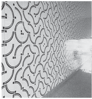 Painel de azulejos com padrões curvos repetidos em um corredor.
