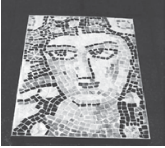 Mosaico formado por pequenas peças claras e escuras que representam um rosto de frente.