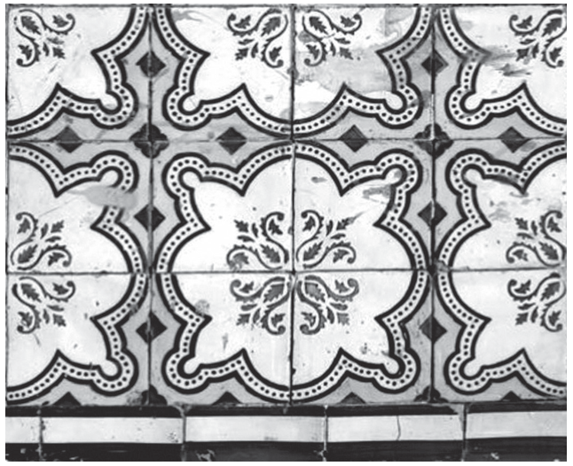 Fotografia em preto e branco de um painel de azulejos tradicionais com padrões florais e geométricos simétricos, dispostos lado a lado.