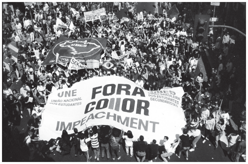 F1 Fotografia de manifestação com grande faixa central onde se lê: "UNE - UNIÃO NACIONAL DOS ESTUDANTES / FORA COLLOR / IMPEACHMENT / UBES - UNIÃO BRASILEIRA DOS ESTUDANTES SECUNDARISTAS", cercada por multidão de manifestantes em uma rua.