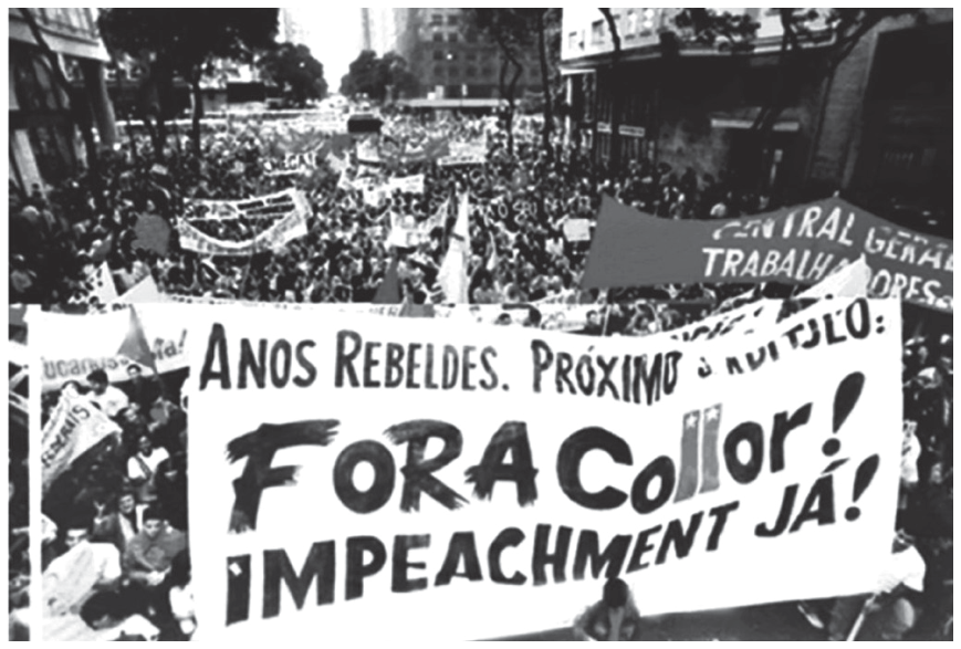 Fotografia em preto e branco de uma manifestação de rua lotada, com uma grande faixa em destaque no primeiro plano em que se lê: "ANOS REBELDES. PRÓXIMO CAPÍTULO: FORA Collor! IMPEACHMENT JÁ!". Ao redor e ao fundo, vê-se a multidão e outras faixas, como uma onde se lê "CENTRAL GERAL DOS TRABALHADORES".