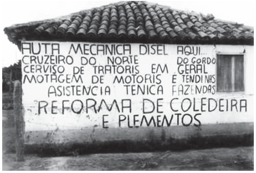 Fotografia da parede externa de uma casa de alvenaria simples e rústica, onde foi pintado em letras maiúsculas pretas o anúncio de uma oficina mecânica: "AUTA MECANICA DISEL AQUI... CRUZEIRO DO NORTE DO GORDO CERVIÇO DE TRATORIS EM GERAL MOTAGEM DE MOTORIS E TENDI NAS FAZENDAS ASISTENCIA TENICA REFORMA DE COLEDEIRA E PLEMENTOS".